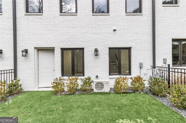 rear view of property featuring ac unit and a lawn