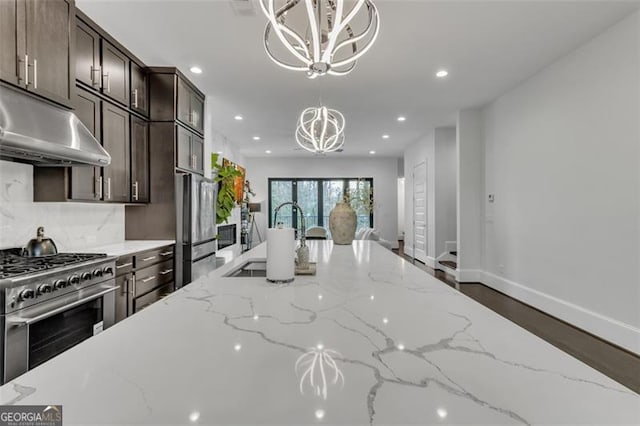 kitchen with stainless steel appliances, light stone countertops, hanging light fixtures, and a notable chandelier