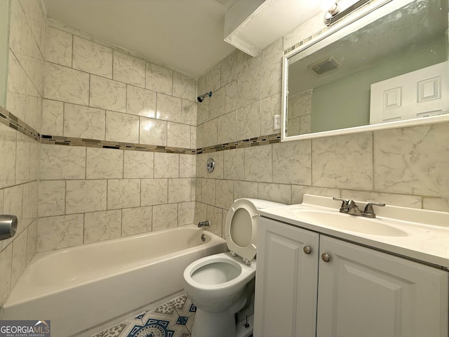 full bathroom with tile walls, vanity, tiled shower / bath, decorative backsplash, and toilet