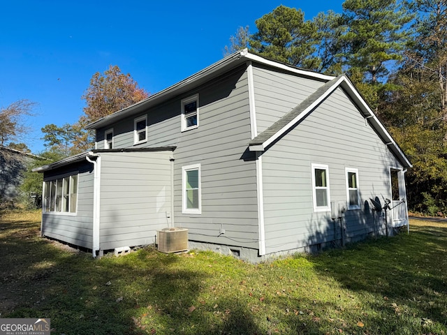 rear view of house featuring a lawn and central air condition unit