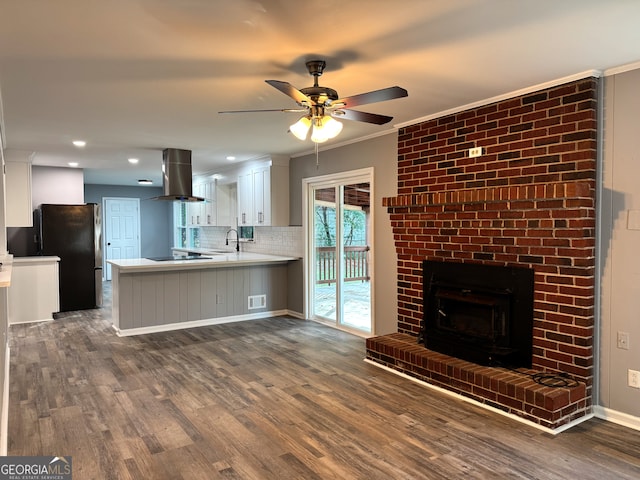 kitchen featuring white cabinetry, black appliances, island exhaust hood, dark hardwood / wood-style flooring, and kitchen peninsula