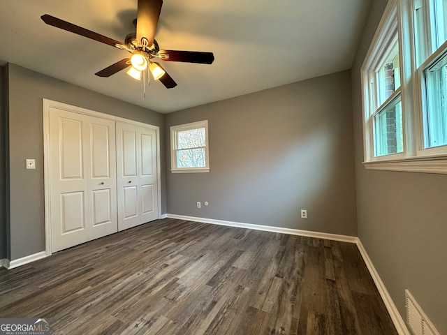 unfurnished bedroom with a closet, dark hardwood / wood-style floors, and ceiling fan