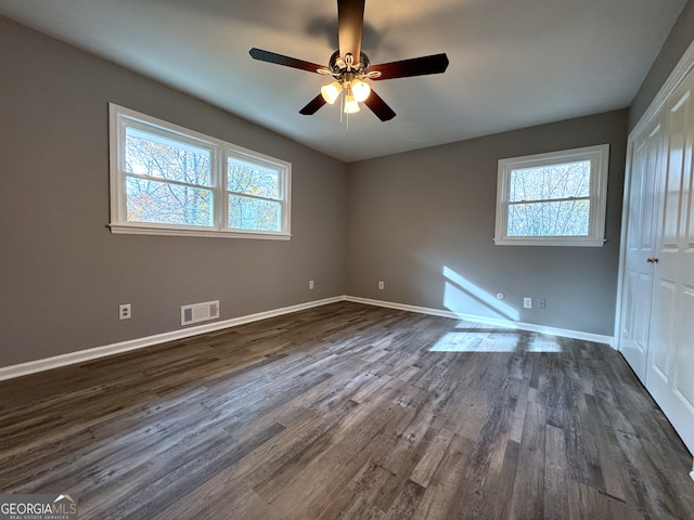 unfurnished room featuring ceiling fan, dark hardwood / wood-style floors, and a wealth of natural light