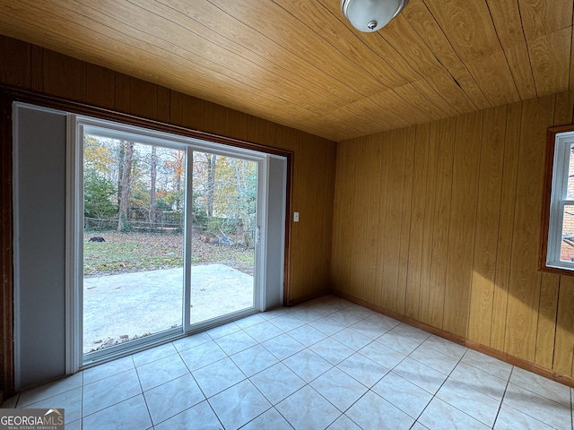 tiled empty room featuring wooden ceiling and wooden walls