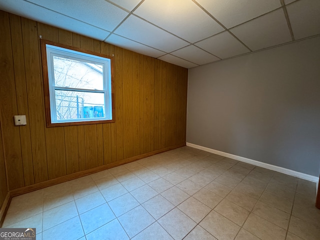 spare room featuring wood walls and a drop ceiling