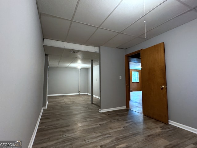 basement with dark hardwood / wood-style flooring and a paneled ceiling