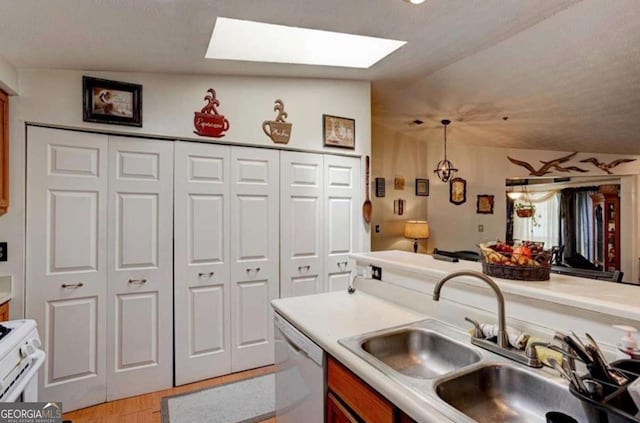 kitchen with sink, pendant lighting, white appliances, vaulted ceiling with skylight, and light hardwood / wood-style floors