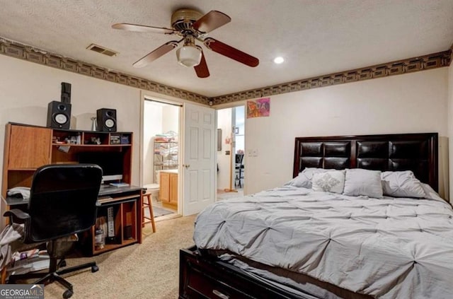 bedroom featuring ceiling fan, light carpet, a textured ceiling, and ensuite bath