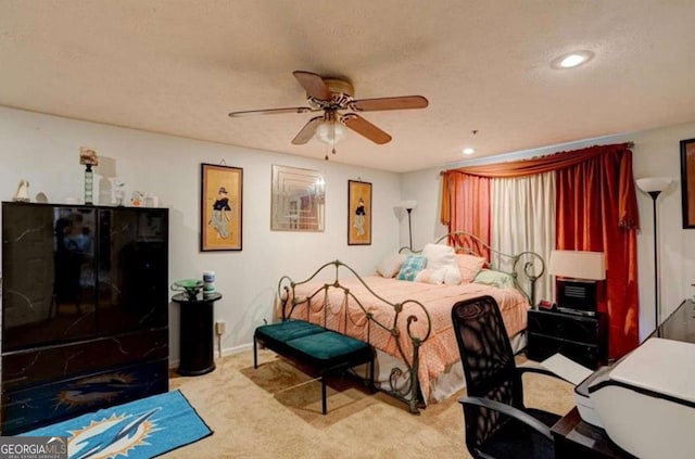 carpeted bedroom featuring ceiling fan and a textured ceiling