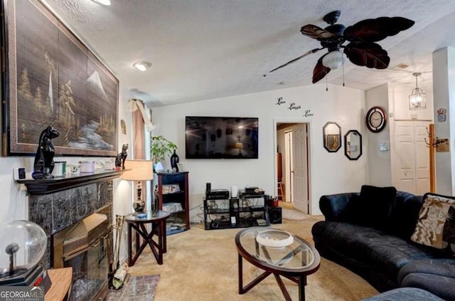 living room with vaulted ceiling, ceiling fan, a high end fireplace, light carpet, and a textured ceiling