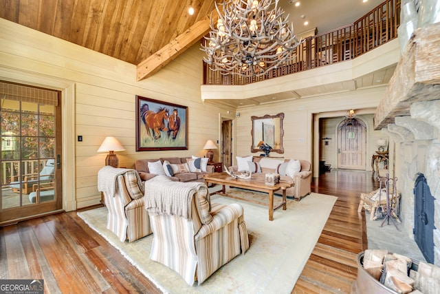 living room featuring wood ceiling, beam ceiling, wooden walls, a towering ceiling, and wood-type flooring