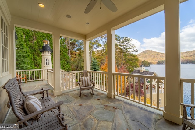 sunroom / solarium with a water and mountain view and ceiling fan