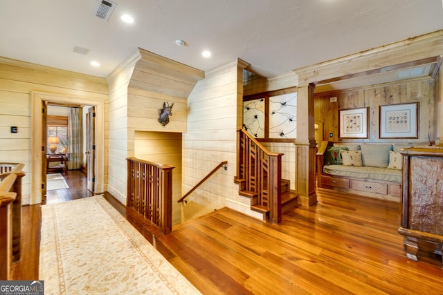 corridor featuring crown molding, hardwood / wood-style floors, and wood walls