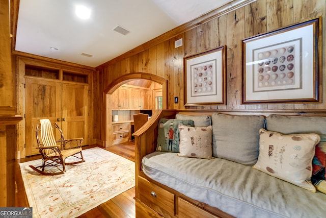 living room with light hardwood / wood-style floors and wood walls