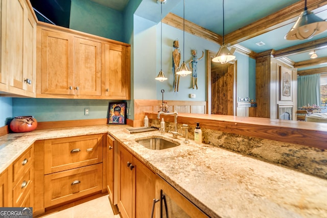 kitchen featuring ornamental molding, light stone countertops, sink, and hanging light fixtures