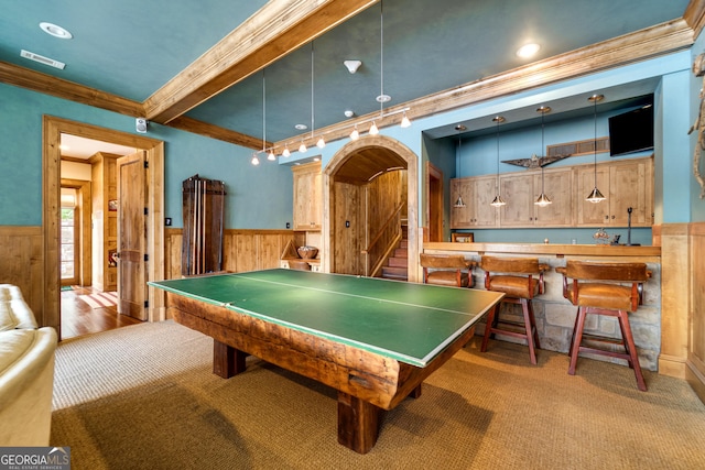 rec room featuring indoor bar, ornamental molding, wooden walls, and light carpet