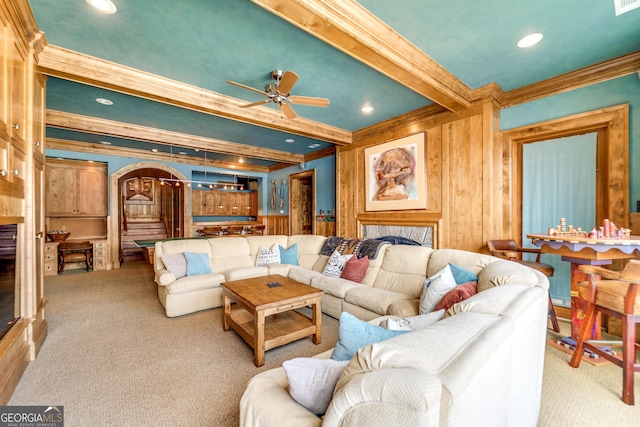 carpeted living room featuring beam ceiling, ornamental molding, and ceiling fan