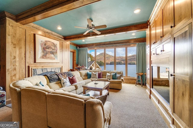 living room featuring ceiling fan, carpet flooring, a water view, beamed ceiling, and wood walls