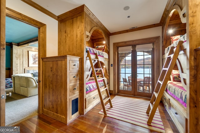 entryway featuring french doors, crown molding, hardwood / wood-style flooring, and a water view