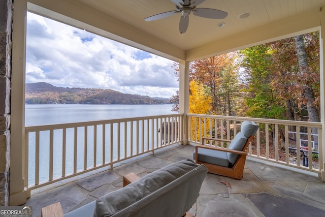 balcony featuring a water and mountain view and ceiling fan