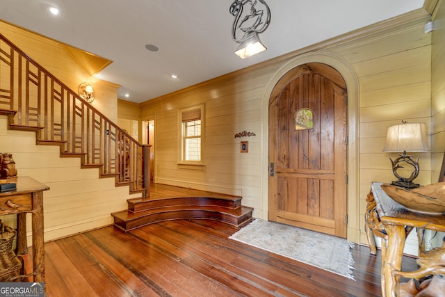 entrance foyer featuring hardwood / wood-style flooring, crown molding, and wood walls