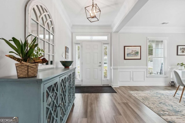 entrance foyer with an inviting chandelier, hardwood / wood-style flooring, and ornamental molding