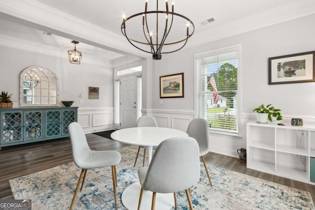 dining room featuring dark wood-type flooring, ornamental molding, and a notable chandelier