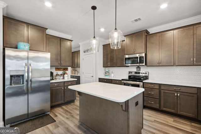 kitchen with appliances with stainless steel finishes, hanging light fixtures, dark brown cabinetry, tasteful backsplash, and ornamental molding