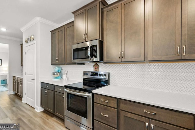 kitchen featuring crown molding, dark brown cabinetry, stainless steel appliances, and decorative backsplash