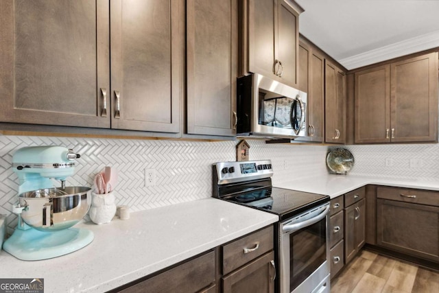 kitchen featuring tasteful backsplash, appliances with stainless steel finishes, dark brown cabinets, and light hardwood / wood-style flooring