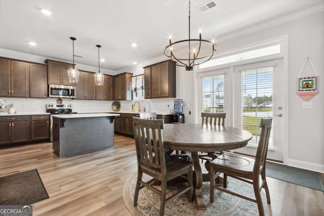 dining room with crown molding, an inviting chandelier, and light hardwood / wood-style flooring