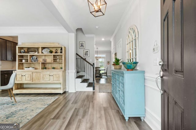 foyer with ornamental molding, light hardwood / wood-style floors, and a chandelier