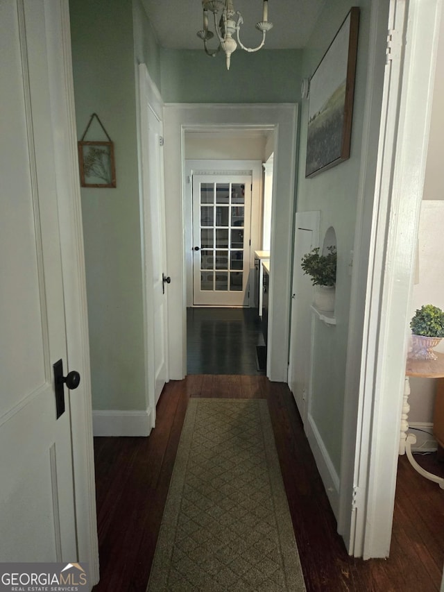 hallway featuring dark hardwood / wood-style flooring and a notable chandelier