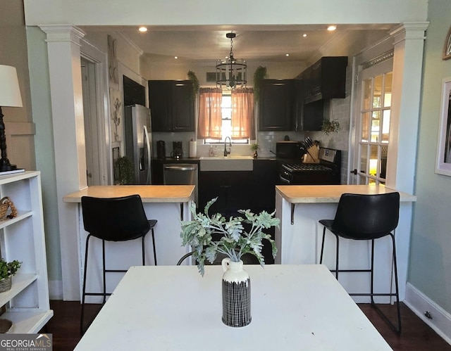 kitchen with stainless steel appliances, kitchen peninsula, decorative columns, and a breakfast bar area