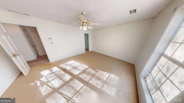 carpeted empty room featuring ceiling fan and a textured ceiling