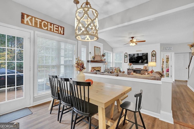 dining room featuring vaulted ceiling, ceiling fan with notable chandelier, and hardwood / wood-style floors