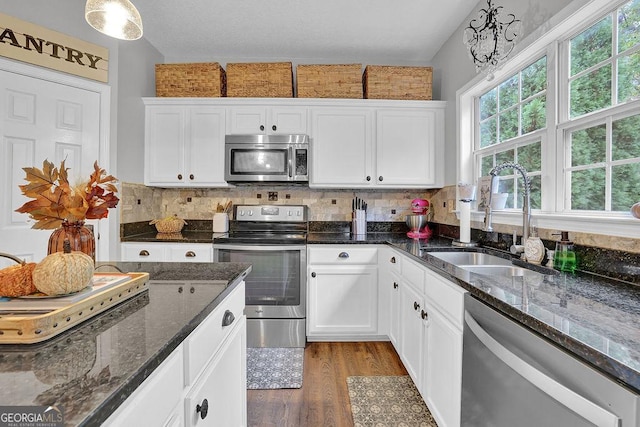 kitchen featuring sink, white cabinetry, decorative light fixtures, dark stone countertops, and stainless steel appliances