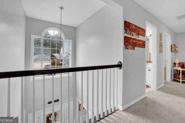 hallway featuring light colored carpet and a textured ceiling