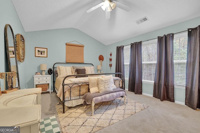 bedroom with ceiling fan, vaulted ceiling, light carpet, and a textured ceiling