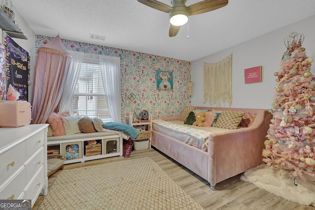 bedroom featuring ceiling fan, a textured ceiling, and light wood-type flooring