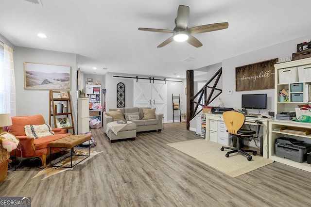 office area featuring ceiling fan, a barn door, and light wood-type flooring