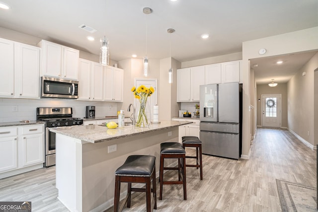 kitchen featuring stainless steel appliances, an island with sink, and white cabinets