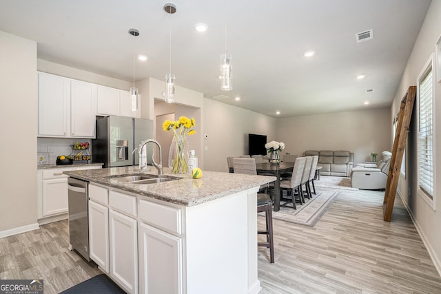 kitchen featuring appliances with stainless steel finishes, a kitchen island with sink, sink, and white cabinets