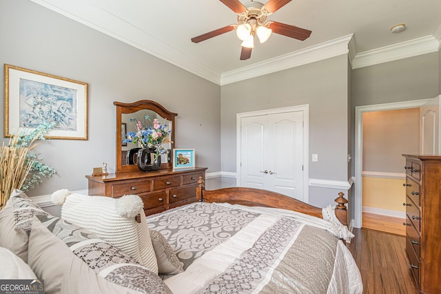 bedroom featuring ornamental molding, ceiling fan, dark hardwood / wood-style flooring, and a closet