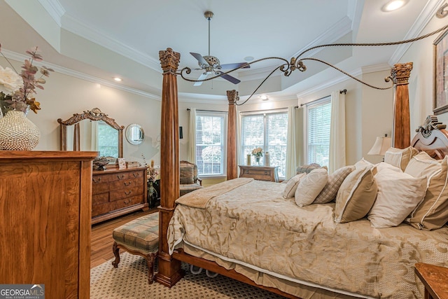 bedroom featuring crown molding, ceiling fan, a tray ceiling, and light hardwood / wood-style floors