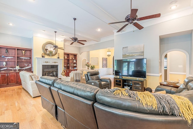 living room with ceiling fan, ornamental molding, light hardwood / wood-style floors, and beamed ceiling