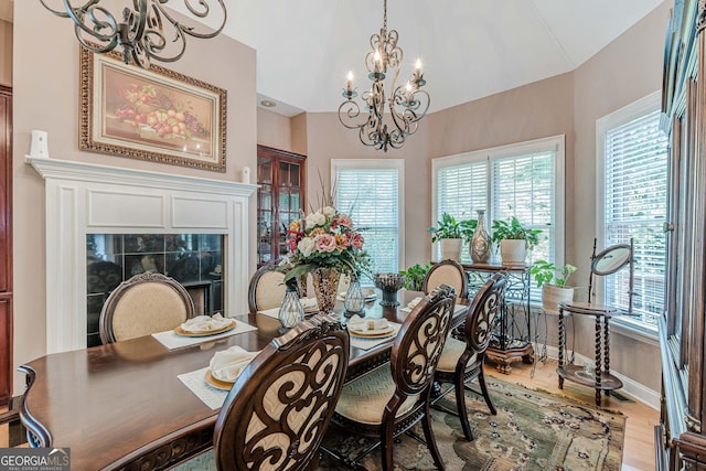 dining room featuring an inviting chandelier, hardwood / wood-style flooring, plenty of natural light, and vaulted ceiling