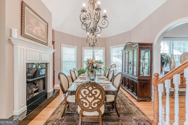 dining space featuring plenty of natural light, vaulted ceiling, light hardwood / wood-style flooring, and a notable chandelier