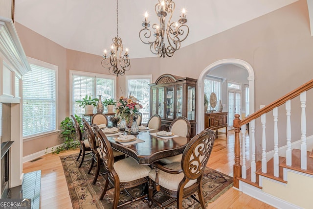 dining area with lofted ceiling, a notable chandelier, and light wood-type flooring