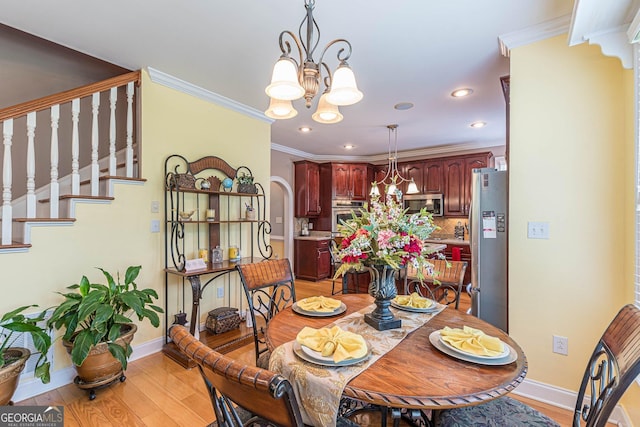 dining room featuring crown molding, light wood-type flooring, and a notable chandelier